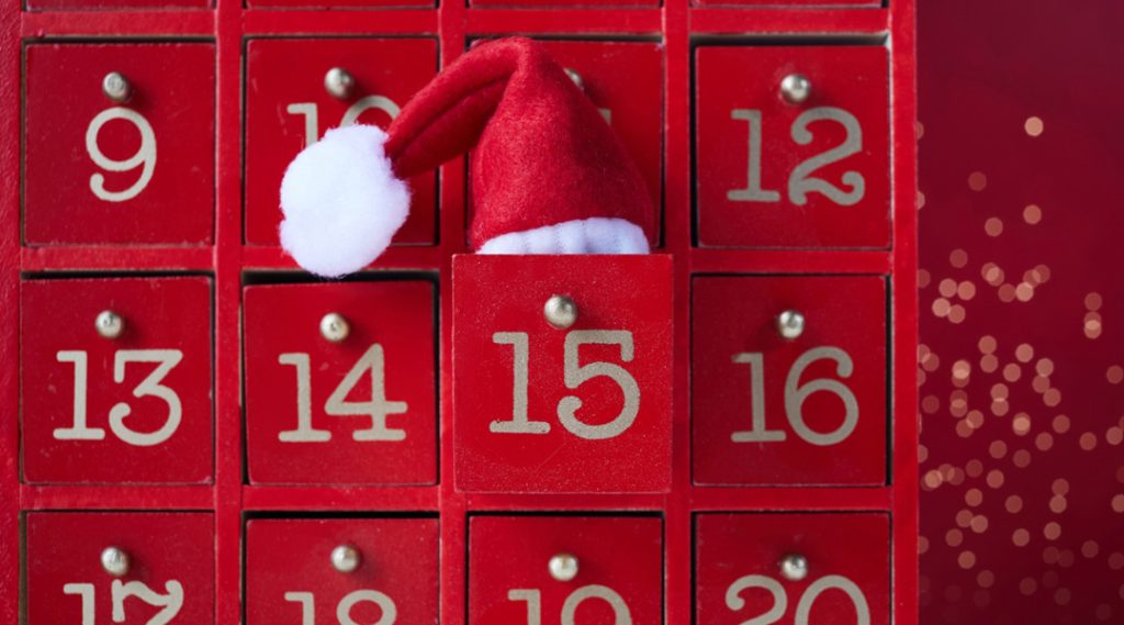 Red calendar with doors for countdown to Christmas with a red Santa hat.